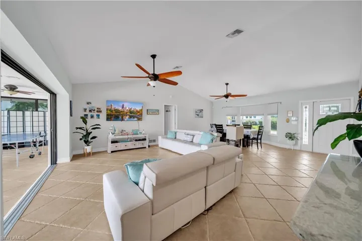 Living room with light tile patterned floors, a ceiling fan, and high vaulted ceiling