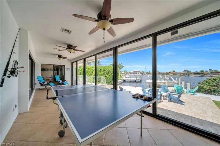 Playroom featuring a water view, a ceiling fan, and light tile patterned floors