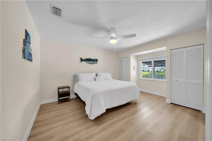 Bedroom with multiple closets, light wood-style flooring, and a ceiling fan