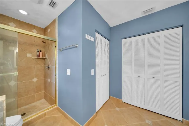 Bathroom with a closet, a shower stall, and tile patterned floors