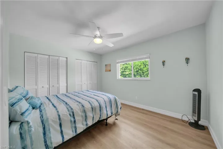 Bedroom with multiple closets, wood finished floors, and a ceiling fan