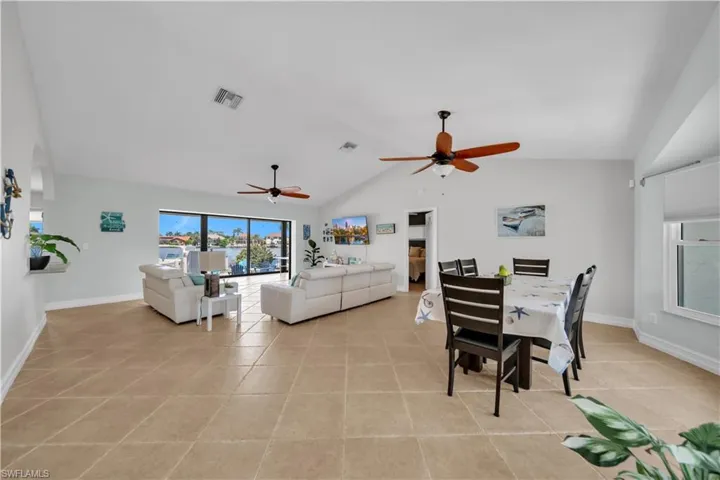 Dining area featuring vaulted ceiling, light tile patterned floors, and a ceiling fan