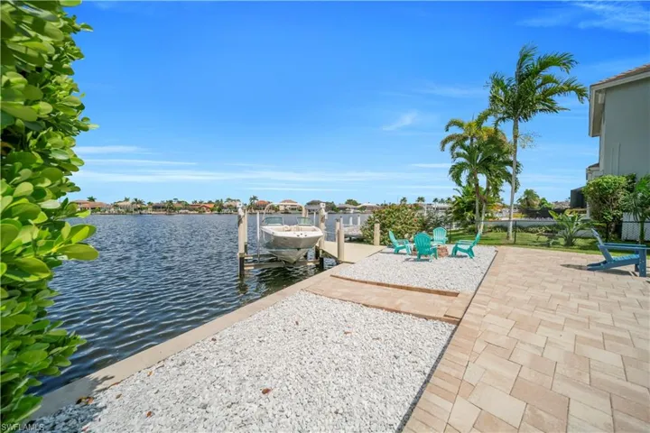 Dock area with a water view, boat lift, and a patio area