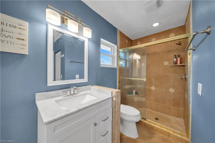 Full bathroom with a stall shower, vanity, and light tile patterned floors