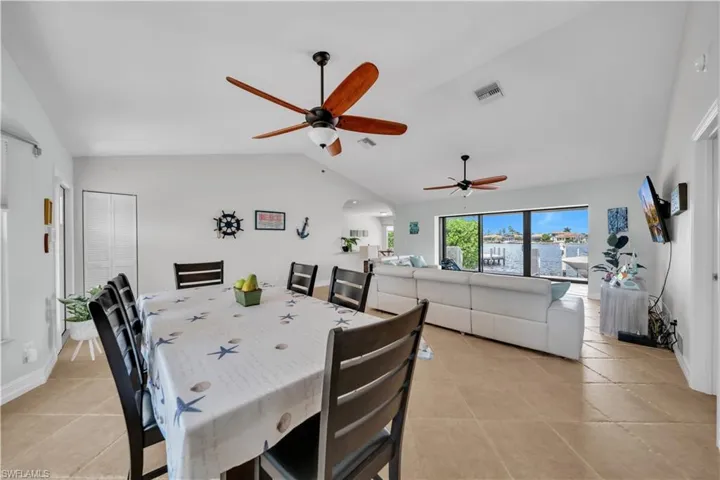 Dining area with lofted ceiling, light tile patterned floors, arched walkways, and a ceiling fan