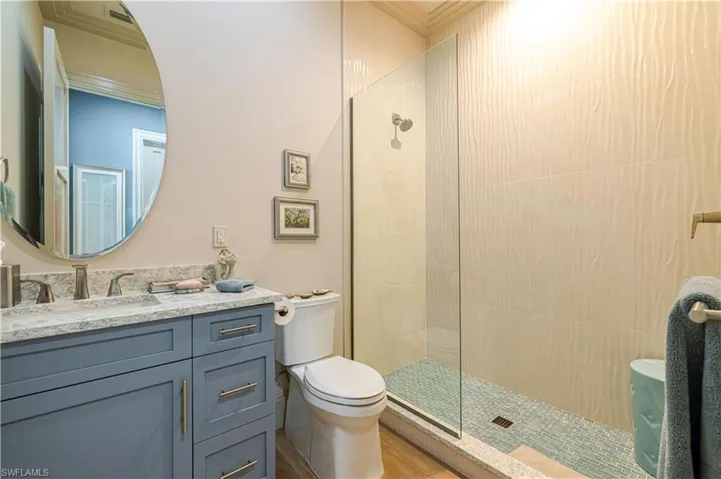 Bathroom featuring a glass-enclosed shower with textured wall tiles and a mosaic tile floor