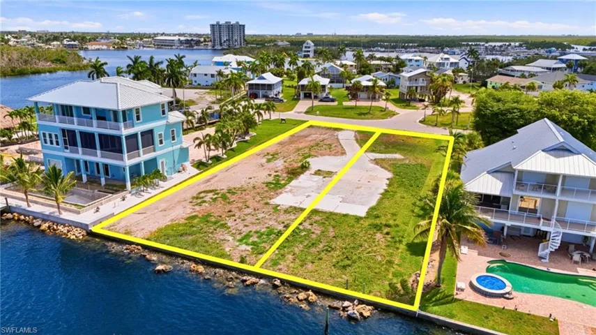Waterfront lot featuring a partial concrete driveway and grass coverage - Virtually Edited Image