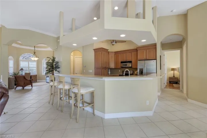 Kitchen featuring a large island with breakfast bar, stainless steel appliances. View toward formal dining room or den.