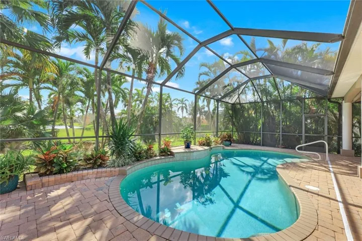 View of pool featuring a patio area, lanai and mature landscaping