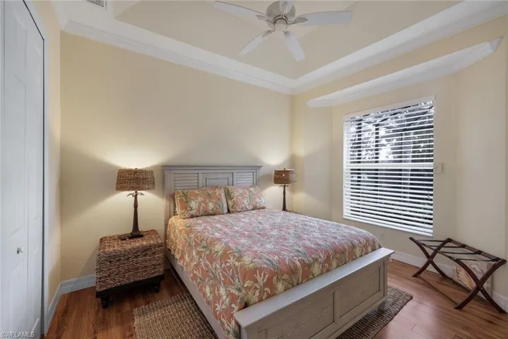 Guest Bedroom #1 with tray ceiling, wood floor and view of pool area