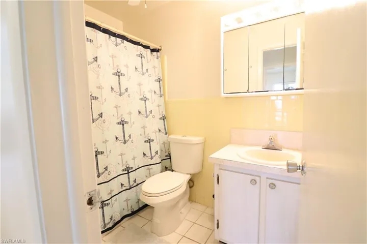 Bathroom featuring decorative backsplash, tile walls, toilet, tile patterned floors, and vanity