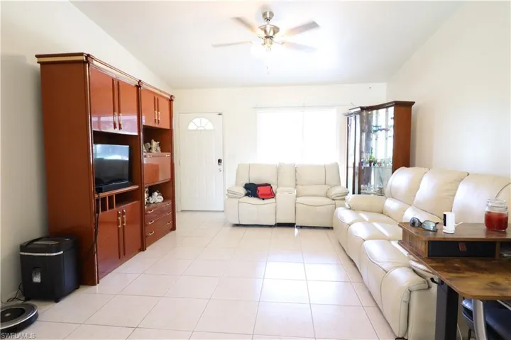 Tiled living room featuring lofted ceiling and ceiling fan