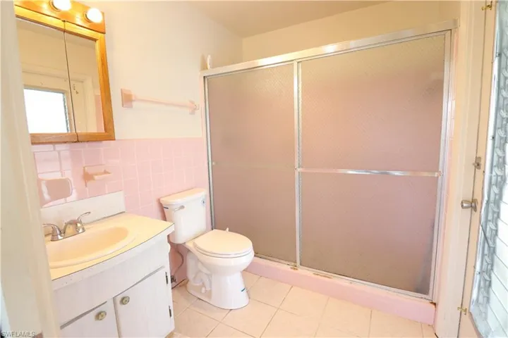 Bathroom featuring tasteful backsplash, toilet, tile walls, an enclosed shower, and vanity