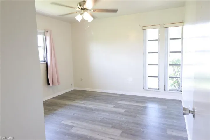 Spare room with ceiling fan, wood-type flooring, and plenty of natural light