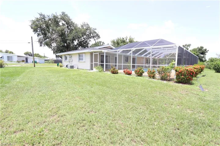 Back of property featuring a lanai, a yard, and cooling unit