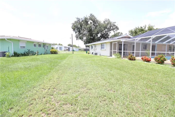 View of yard featuring glass enclosure, central AC unit, and a swimming pool