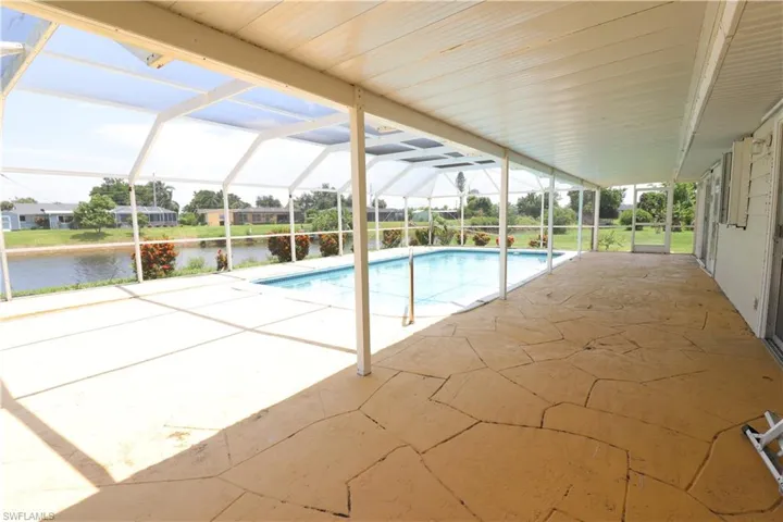 View of pool with glass enclosure and a patio area