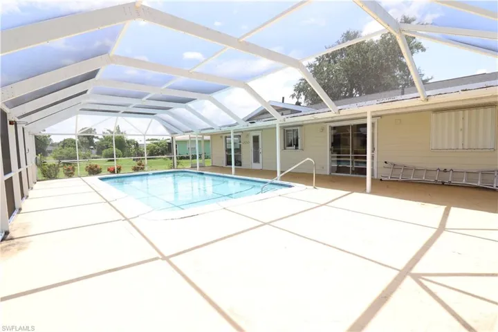 View of pool with glass enclosure and a patio area