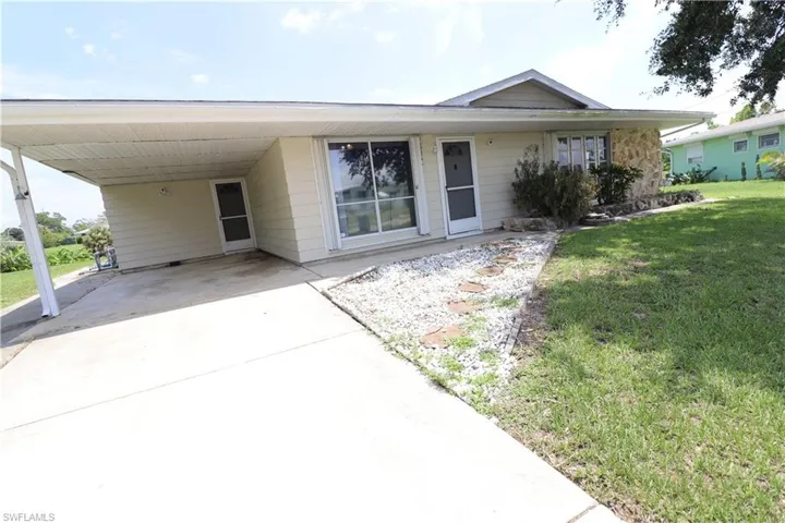 View of front facade with a front yard and a carport