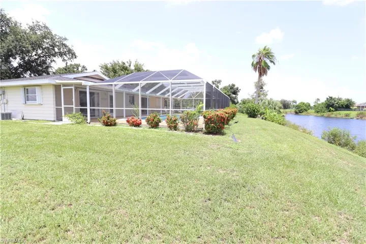 Rear view of property with enclosure, a water view, and a yard
