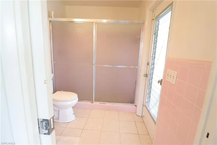 Bathroom featuring tile walls, toilet, tile patterned floors, and a wealth of natural light
