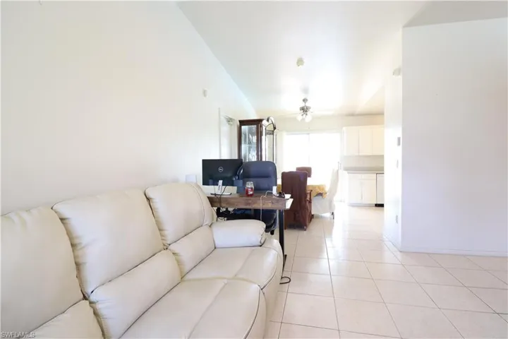Living room with ceiling fan and light tile patterned flooring