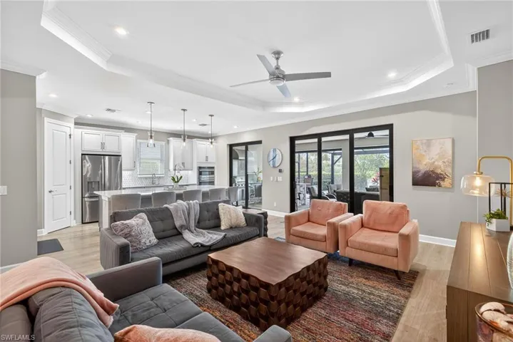 Living area with light wood-style flooring, crown molding, ceiling fan, and recessed lighting and crown molding
