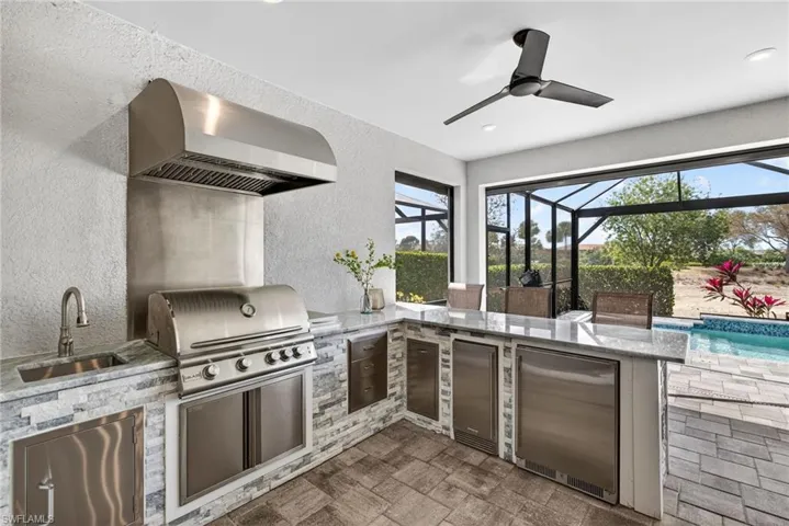 View of outdoor kitchen featuring a grill, refrigerator, ice maker, garbage and storage