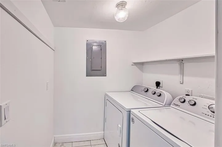 Laundry room featuring hookup for an electric dryer, electric panel, and light tile patterned flooring