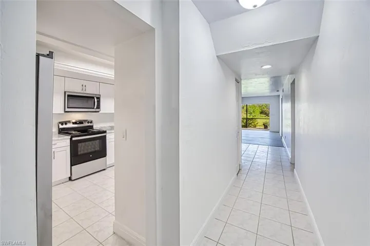 Hallway featuring light tile patterned flooring and baseboards