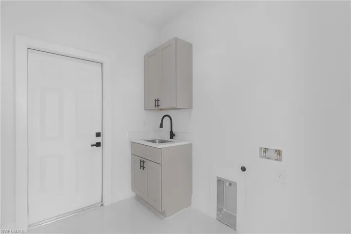 Clothes washing area featuring hookup for an electric dryer, sink, cabinets, hookup for a washing machine, and light tile patterned floors