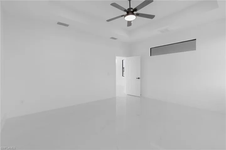 Tiled spare room featuring a raised ceiling and ceiling fan