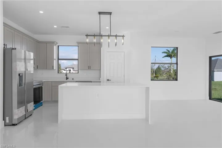 Kitchen with pendant lighting, stainless steel fridge with ice dispenser, a center island, stove, and gray cabinetry