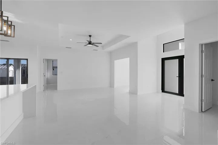 Spare room with a tray ceiling, light tile patterned floors, and ceiling fan
