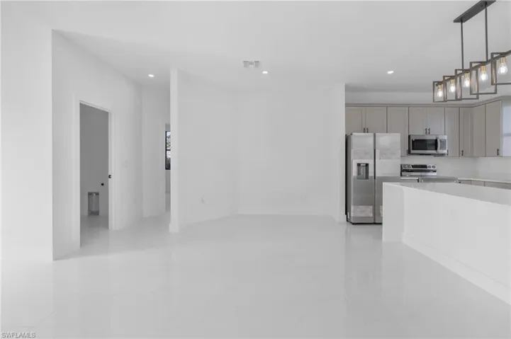 Kitchen with hanging light fixtures, stainless steel appliances, gray cabinets, and light tile patterned floors