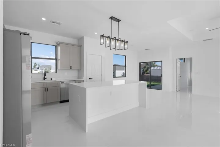 Kitchen featuring gray cabinets, decorative light fixtures, dishwasher, a kitchen island, and light tile patterned floors
