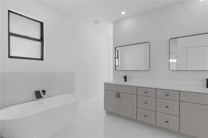 Bathroom featuring dual vanity, tile patterned flooring, and a tub