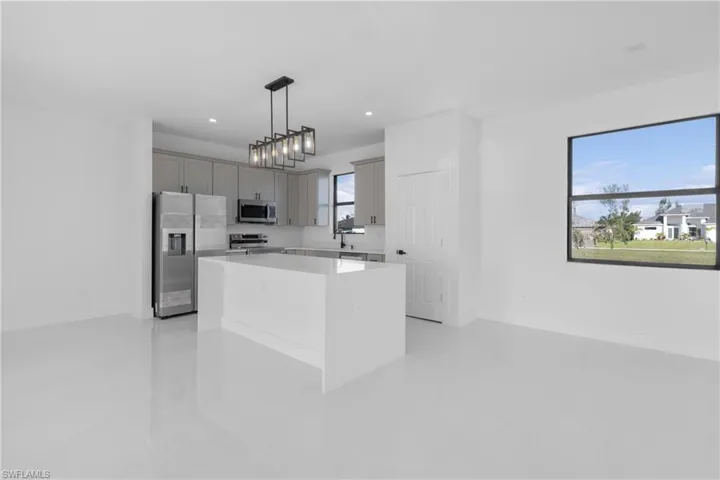 Kitchen with decorative light fixtures, light tile patterned flooring, a kitchen island, appliances with stainless steel finishes, and gray cabinetry
