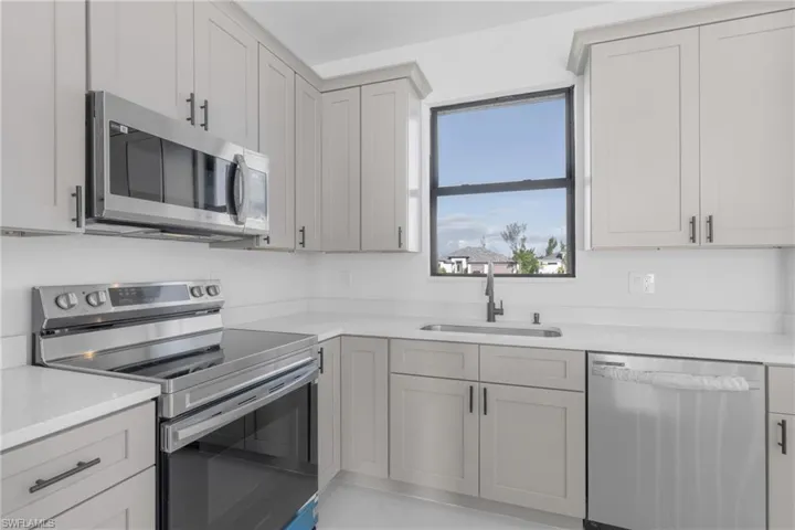 Kitchen with sink, light tile patterned floors, and stainless steel appliances