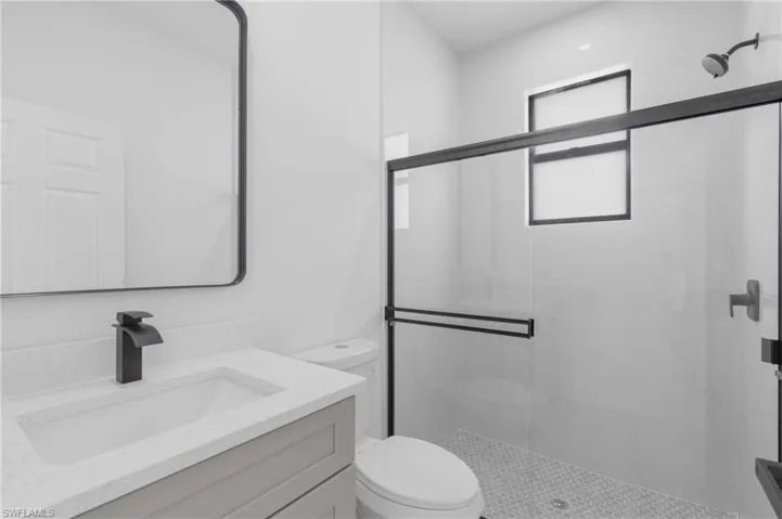 Bathroom featuring a shower with shower door, vanity, and toilet