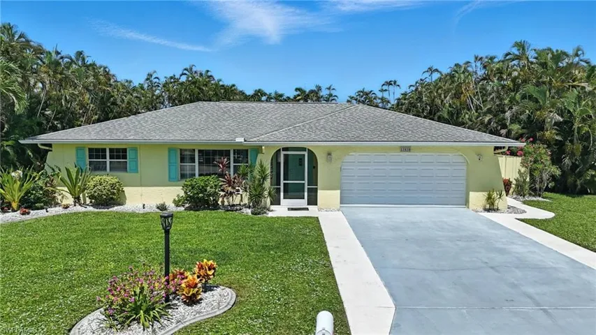 Single story home featuring stucco siding, a front yard, a garage, and driveway