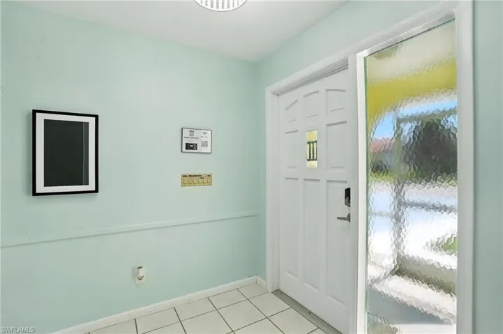 Foyer with light tile patterned floors and baseboards