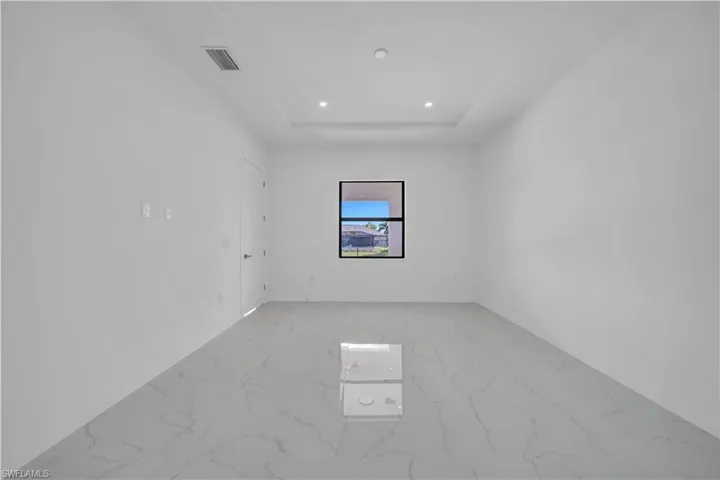 Unfurnished room with light marble finish floors, recessed lighting, and a tray ceiling