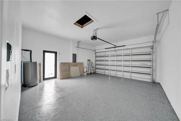 Garage with electric panel, water heater, and a garage door opener