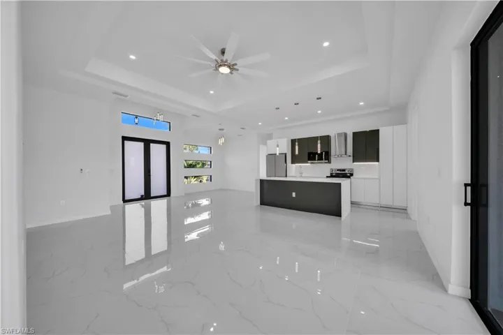 Unfurnished living room with light marble finish flooring, ceiling fan, recessed lighting, french doors, and a raised ceiling