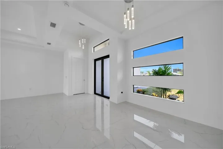 Spare room featuring a chandelier, a high ceiling, and light marble finish flooring