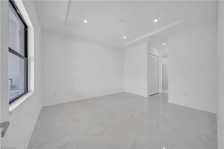Spare room featuring recessed lighting, a raised ceiling, and light marble finish flooring