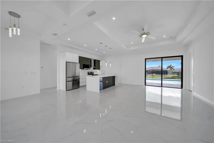Unfurnished living room with a ceiling fan, recessed lighting, light marble finish flooring, and a raised ceiling