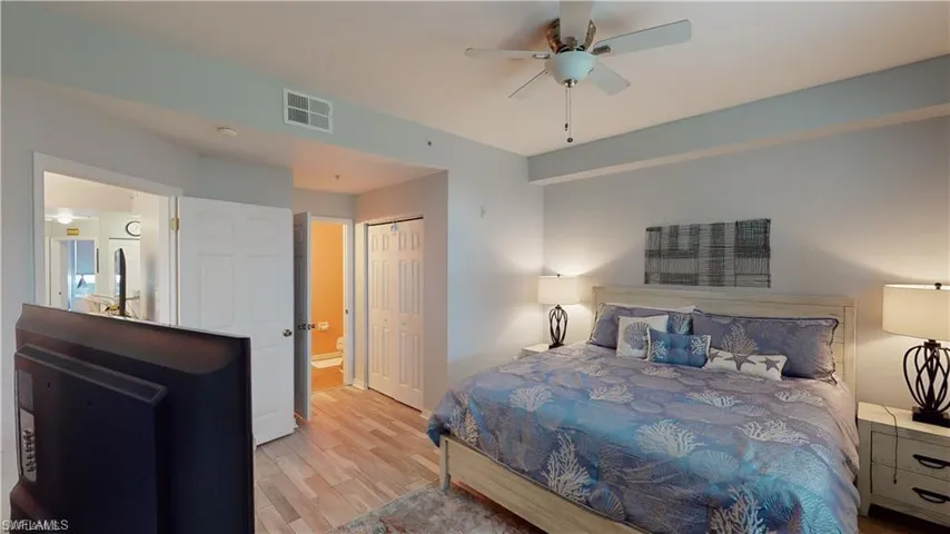 Bedroom with wood finished floors, a closet, ceiling fan, and ensuite bath