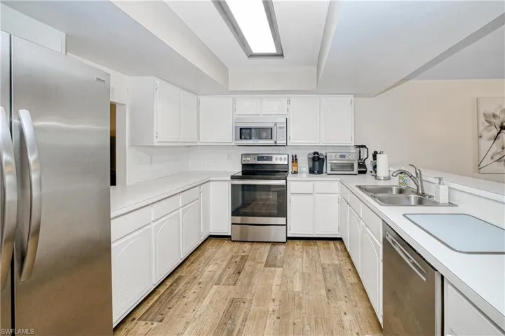Kitchen featuring appliances with stainless steel finishes, light countertops, and white cabinets